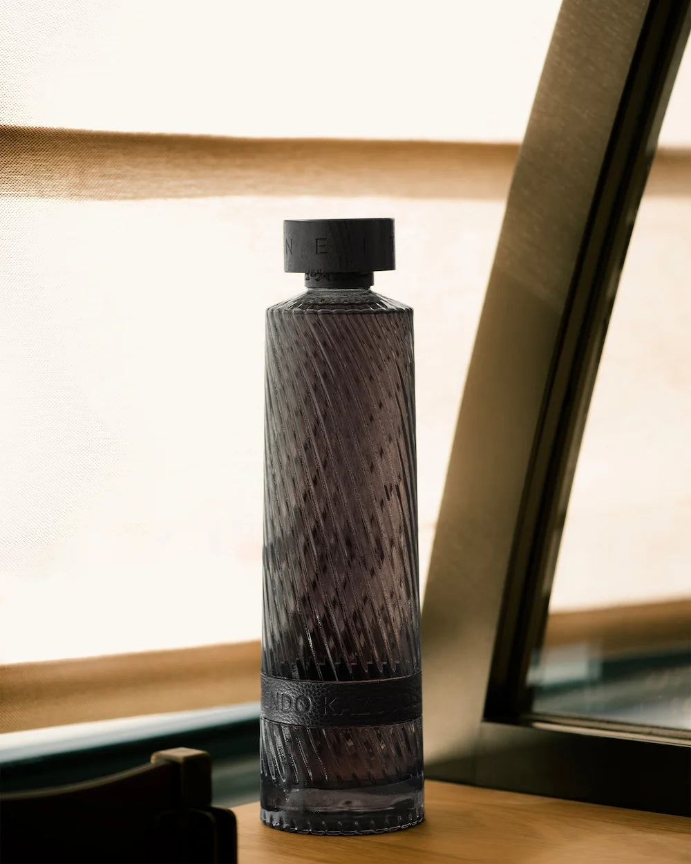 Textured black bottle on a wooden surface with a blurred background